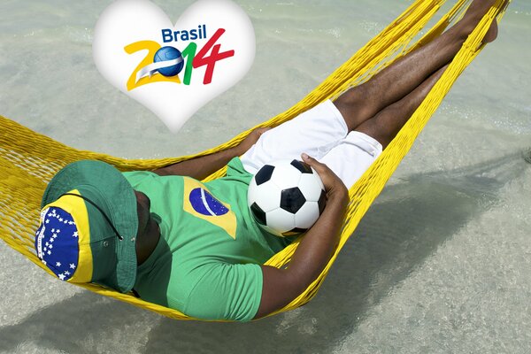 A man is lying on a hammock above the water with a ball in his hands