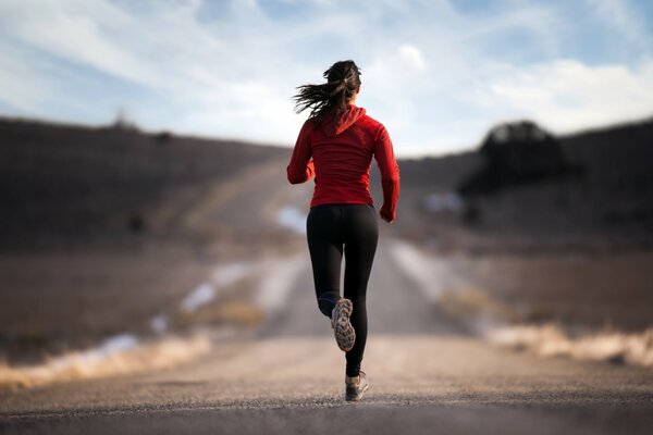 Sportowa dziewczyna biegnie po drodze