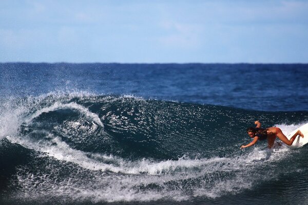 A girl standing on a surfboard on a wave