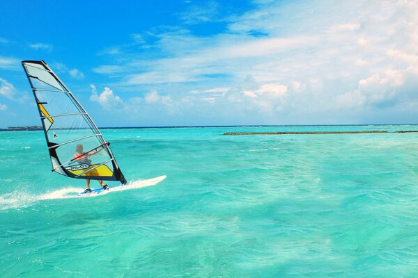 Sailboat on a board in the sea on the horizon clouds