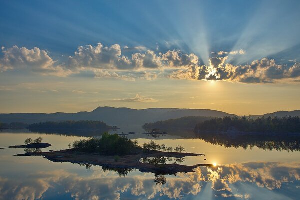 The rays of the sun break through the clouds, and are reflected in the river surface. The forest seems mysterious