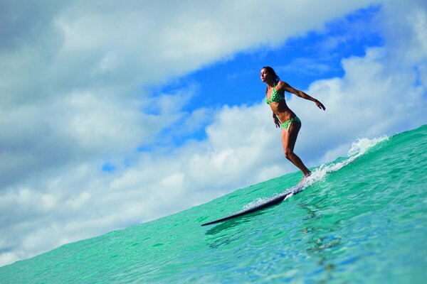Surfer girl on a board against the background of the sea and sky