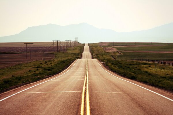 Un largo camino a lo largo del campo directamente a las montañas