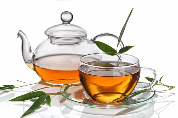 Glass teapot with a cup decorated with leaves