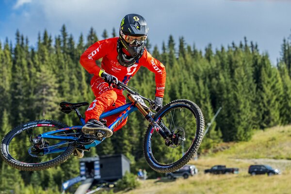 Bicycle race jump of a participant in a red suit on a blue bike