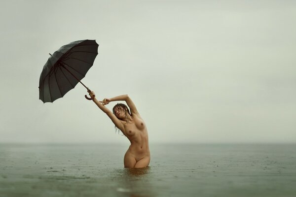 Nacktes Mädchen im Wasser unter einem Regenschirm
