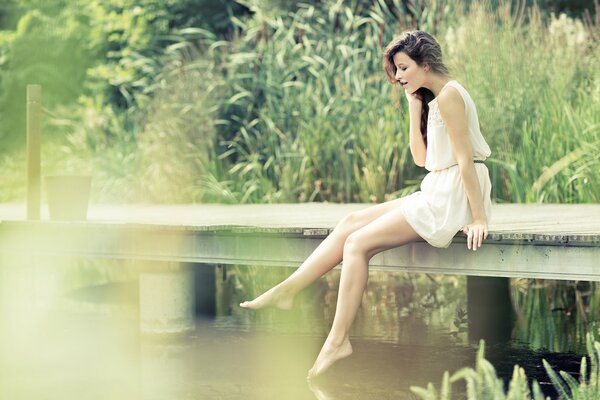 The girl is sitting in nature by the river