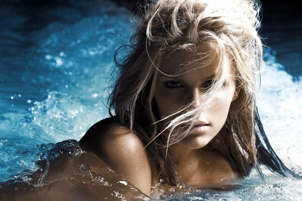 Blondine mit langen Haaren schwimmt im Pool