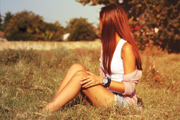 A girl sitting on the grass in the middle of a field