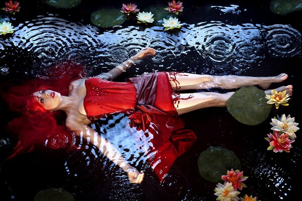 Dziewczyna z czerwonymi włosami leży w wodzie z liliami wodnymi