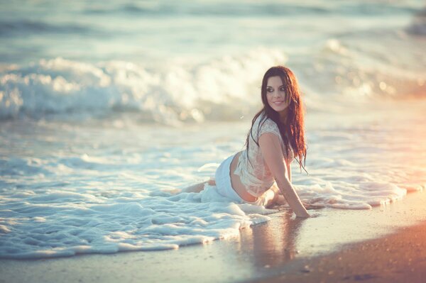 Dziewczyna w mokrej koszulce na plaży na wodzie