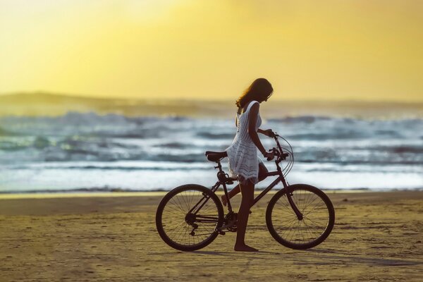 Mädchen auf einem Fahrrad fährt am Strand entlang