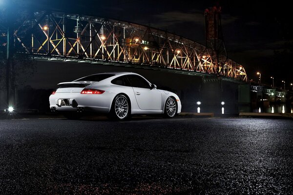 Porsche 911 carrera blanco por la noche cerca del puente