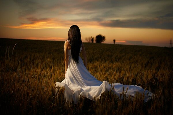 Chica en vestido blanco en el campo al atardecer