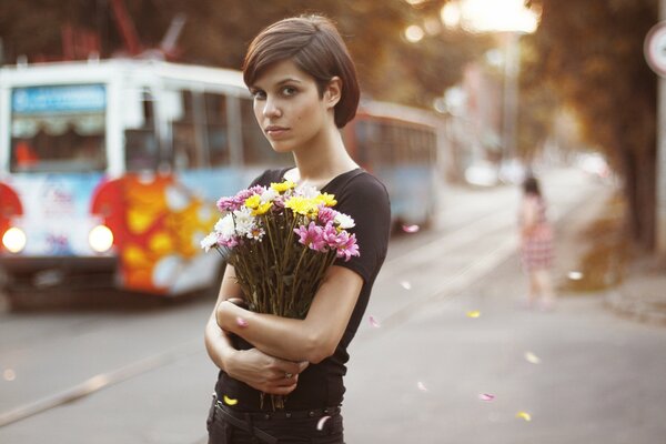 Brown-eyed girl with flowers in the middle of a bustling city