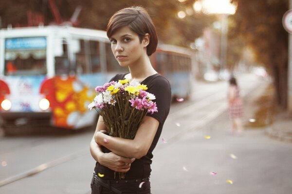 Chica de ojos marrones con flores en medio de una ciudad bulliciosa