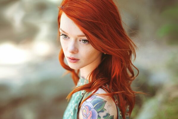 A red-haired beauty with a tattoo on her shoulder