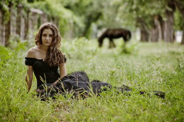 Brunette posing against the background of nature and a horse