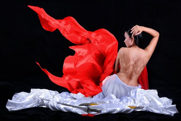 Asian woman with a tattoo of wings on a black background