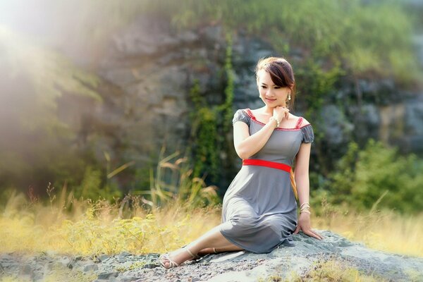 Hermosa chica sentada en las piedras