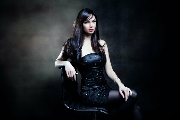 Красивая девушка в чёрном платье на стуле