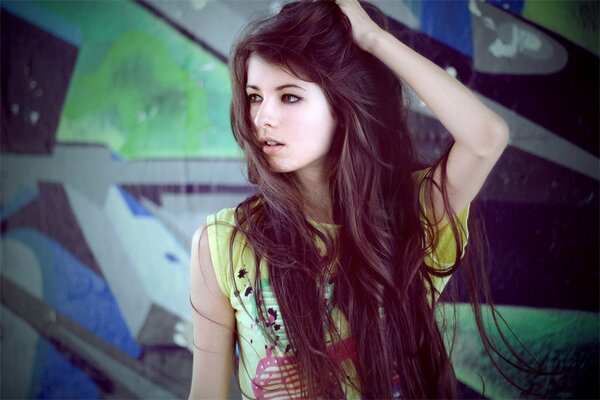 A brown-haired girl on the background of a wall with graffiti