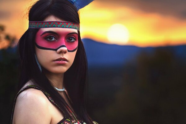 Fille avec un visage peint sur fond de coucher de soleil