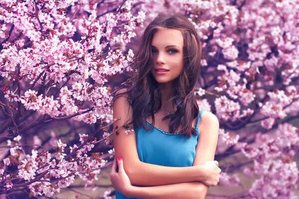 The girl smiles against the background of cherry blossoms