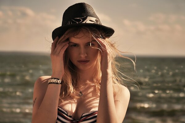 A girl with a hat on the background of clouds and the sea