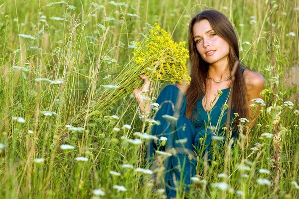 Девушка на летнем поле в окружении полевых цветов