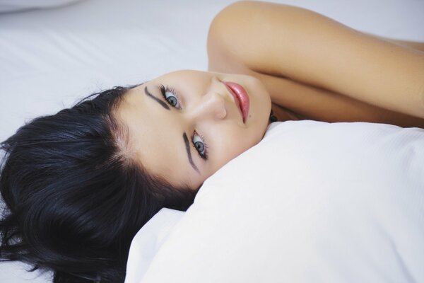 Mädchen mit dunklen Haaren liegt auf dem Bett