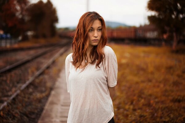 A red-haired girl on the background of an autumn landscape