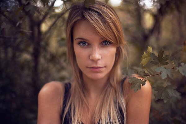 Mädchen mit blonden Haaren auf einem Hintergrund von Bäumen