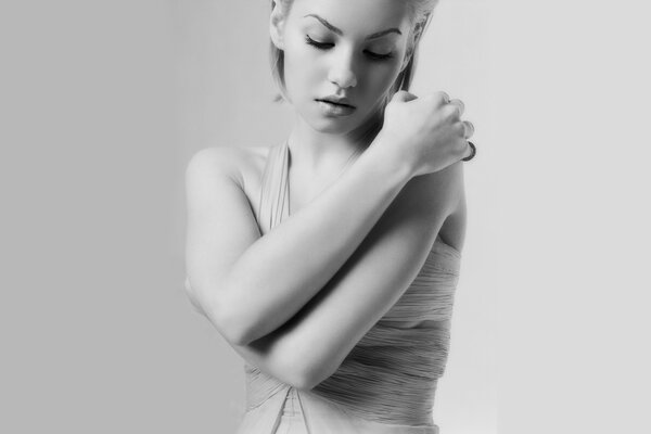 Black and white photo of a girl hugging herself