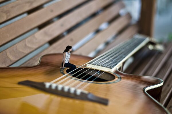 The girl is sitting on the guitar