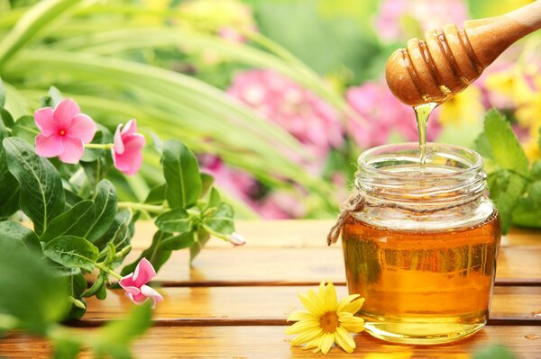 Vaso di miele sul tavolo tra i fiori