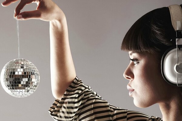 A girl in headphones with a mirror ball