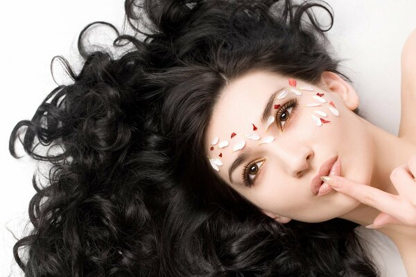 Portrait of a girl with dark hair and petals on her face