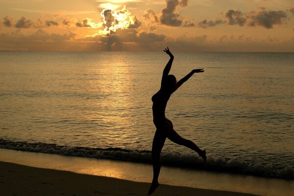 Chica en la playa en el fondo de la puesta de sol