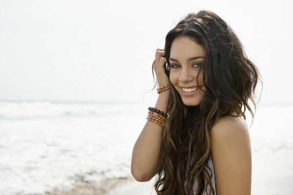 Brown-haired woman with long hair , against the background of the ocean, with a bracelet on her arm