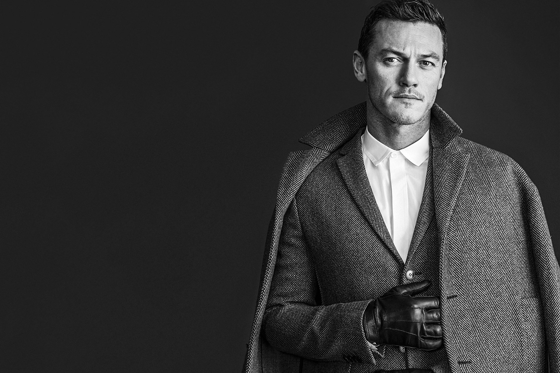 luke evans attore cappotto giacca guanto foto bianco e nero sfondo rivista wwd rodolfo martinez