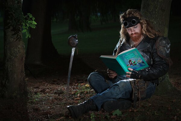 Un hombre de pelo largo con barba Lee un libro de cuentos en el bosque