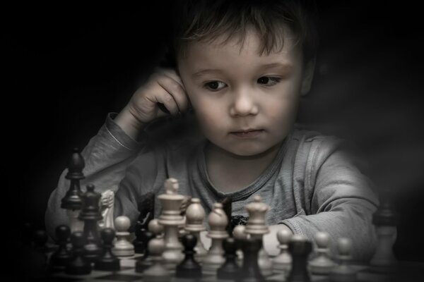 A little boy is playing chess