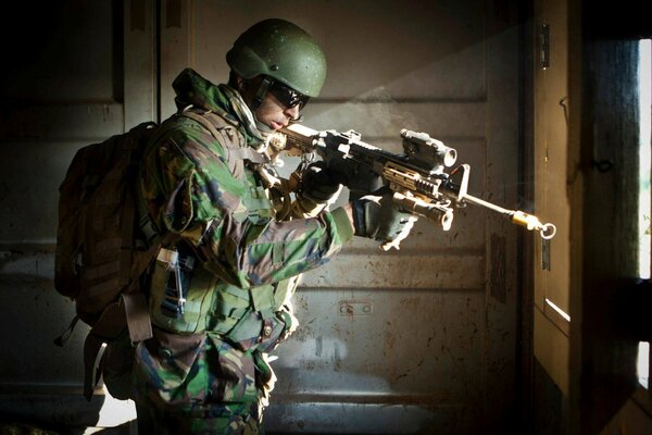 Солдат с оружием целится из здания