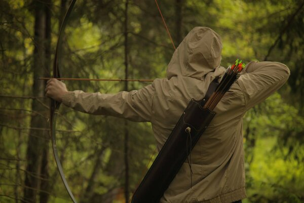 The man took aim in the forest with a bow