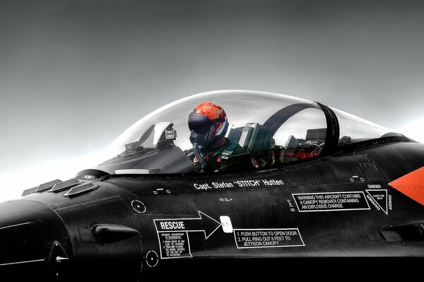 A pilot in a red helmet in a transparent cockpit