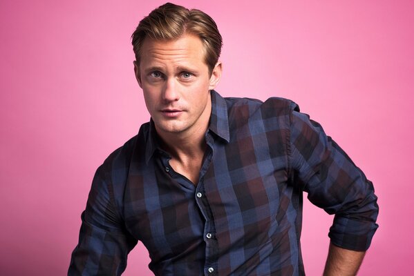 Alexander Skarsgard en chemise sur fond rose