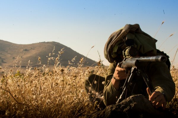 Francotirador con rifle sentado en una emboscada