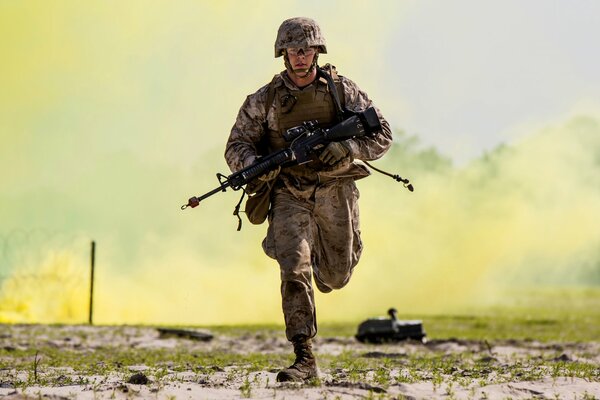 A soldier with a gun runs against the background of smoke