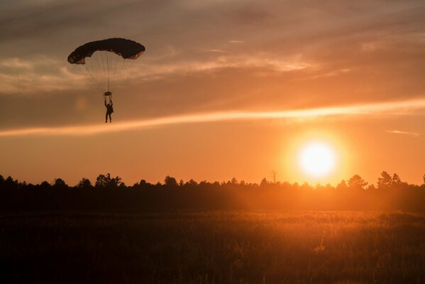 Silhouette eines Fallschirmspringers vor dem Hintergrund der untergehenden Sonne